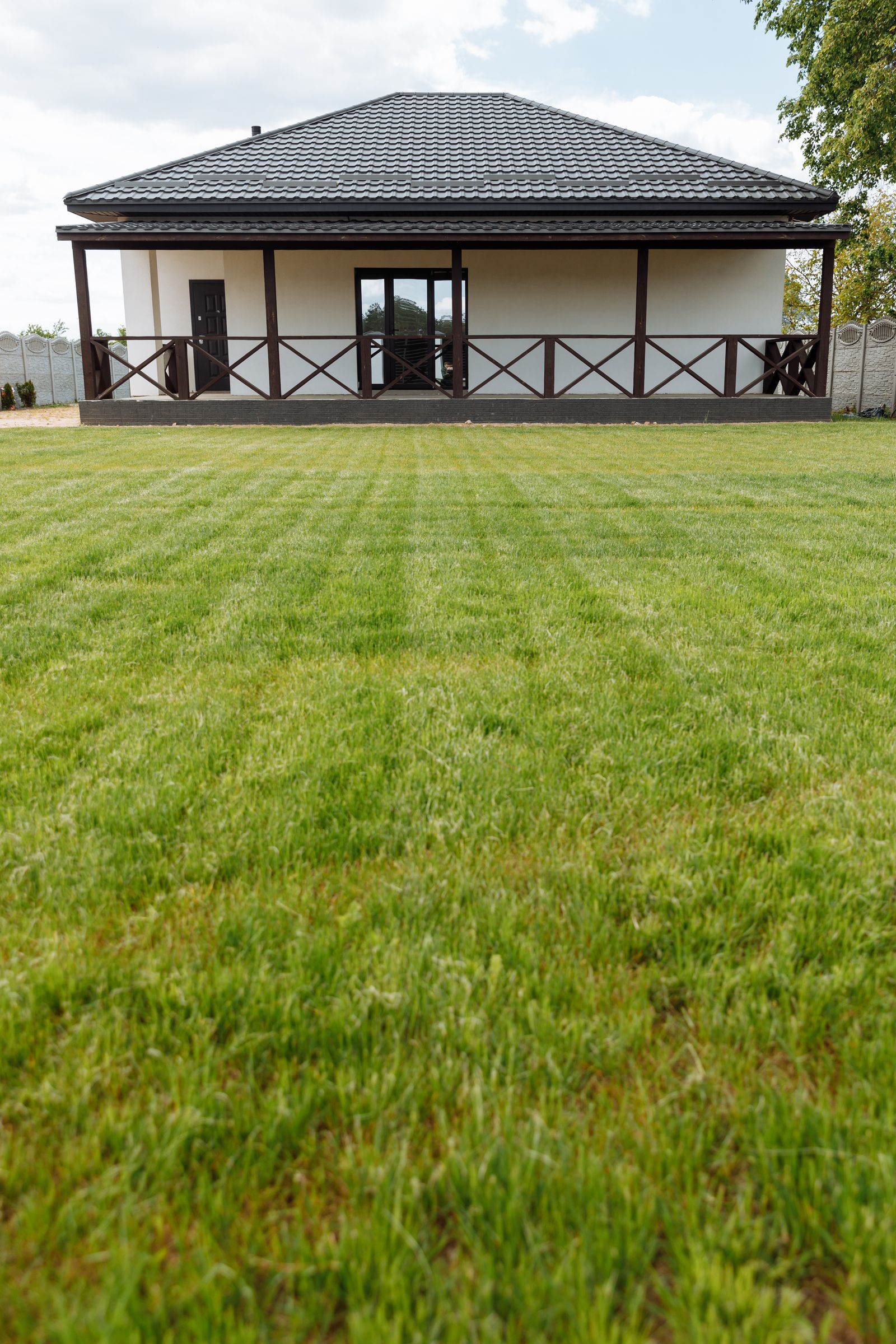 A neatly mown, striped green front lawn in front of a house