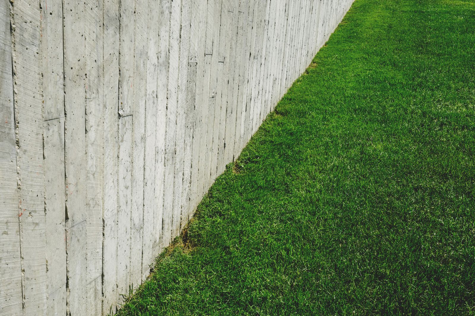 A wooden fence running along the edge of a mowed green lawn