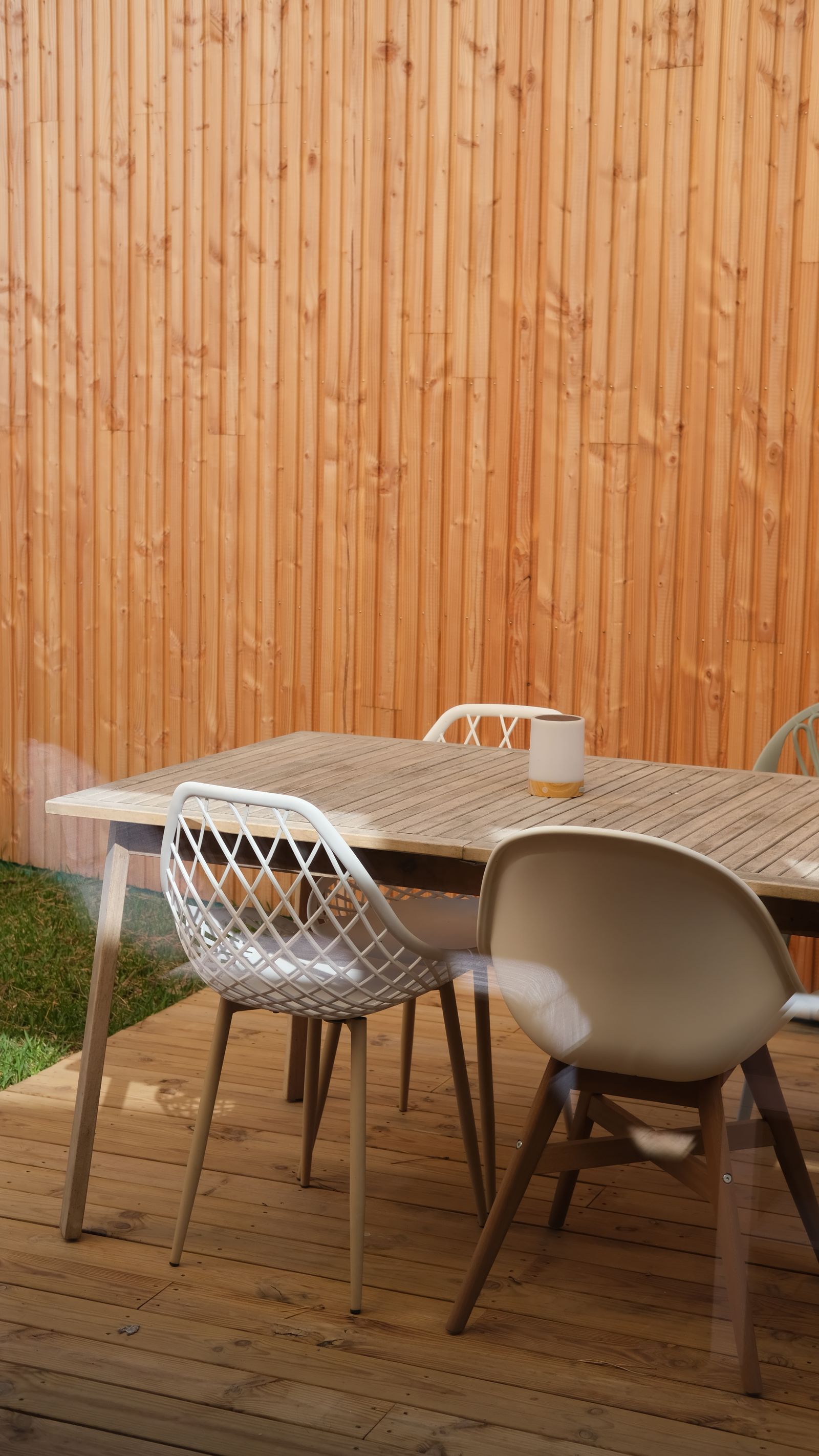 A wooden backyard deck furnished with a table and chairs